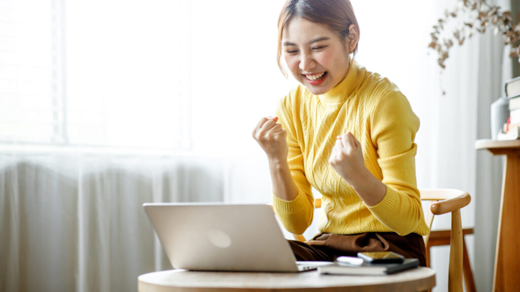 woman excitedly looking at her laptop screen