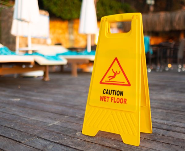 Wet floor caution sign on hotel terrace wooden floor