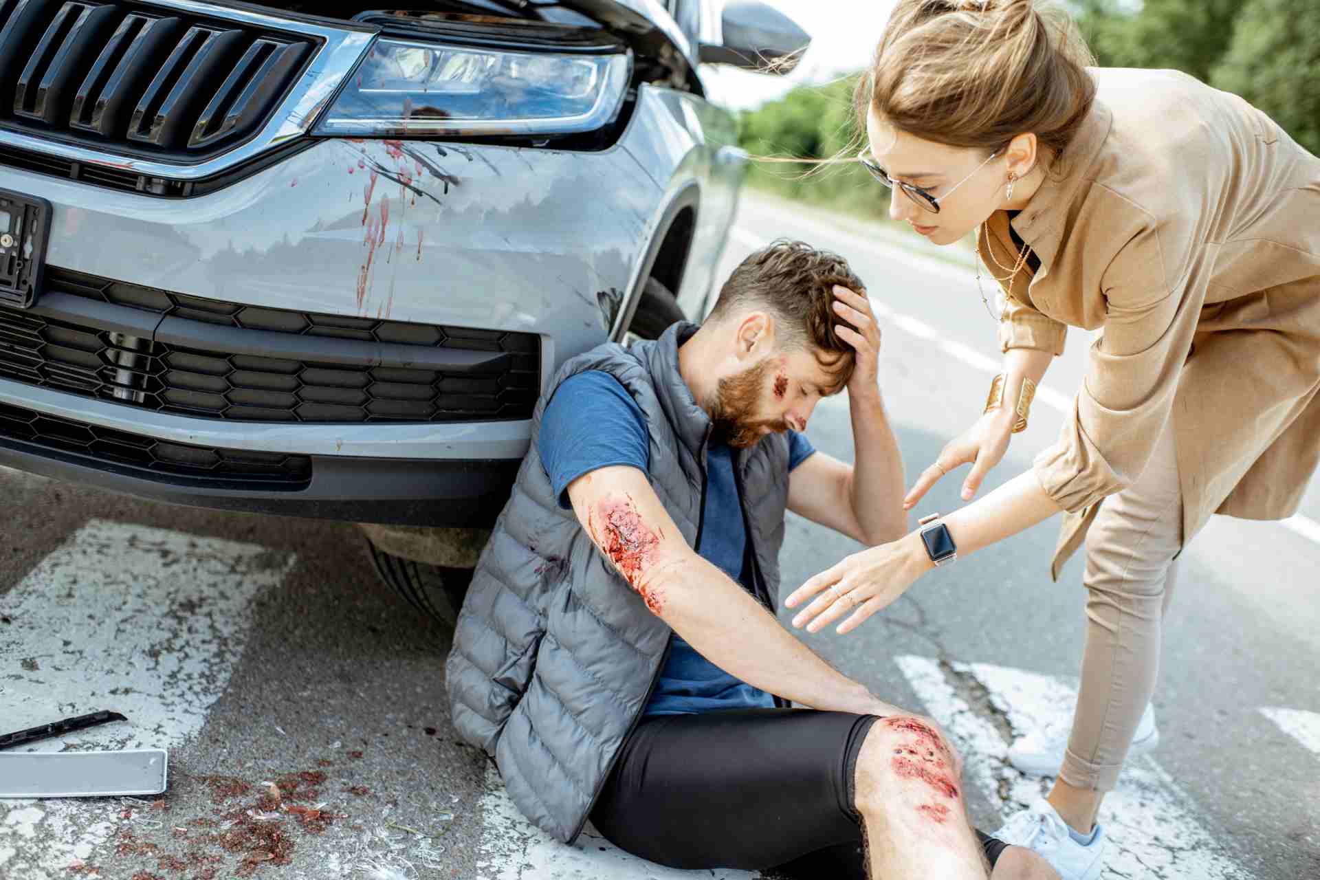 A man who suffered a pedestrian accident being helped by a woman