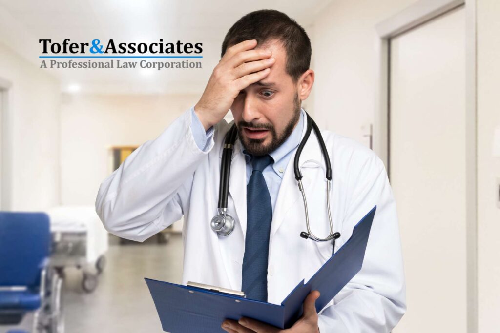 Distressed doctor holding his head while reading a wrongful death suit in California