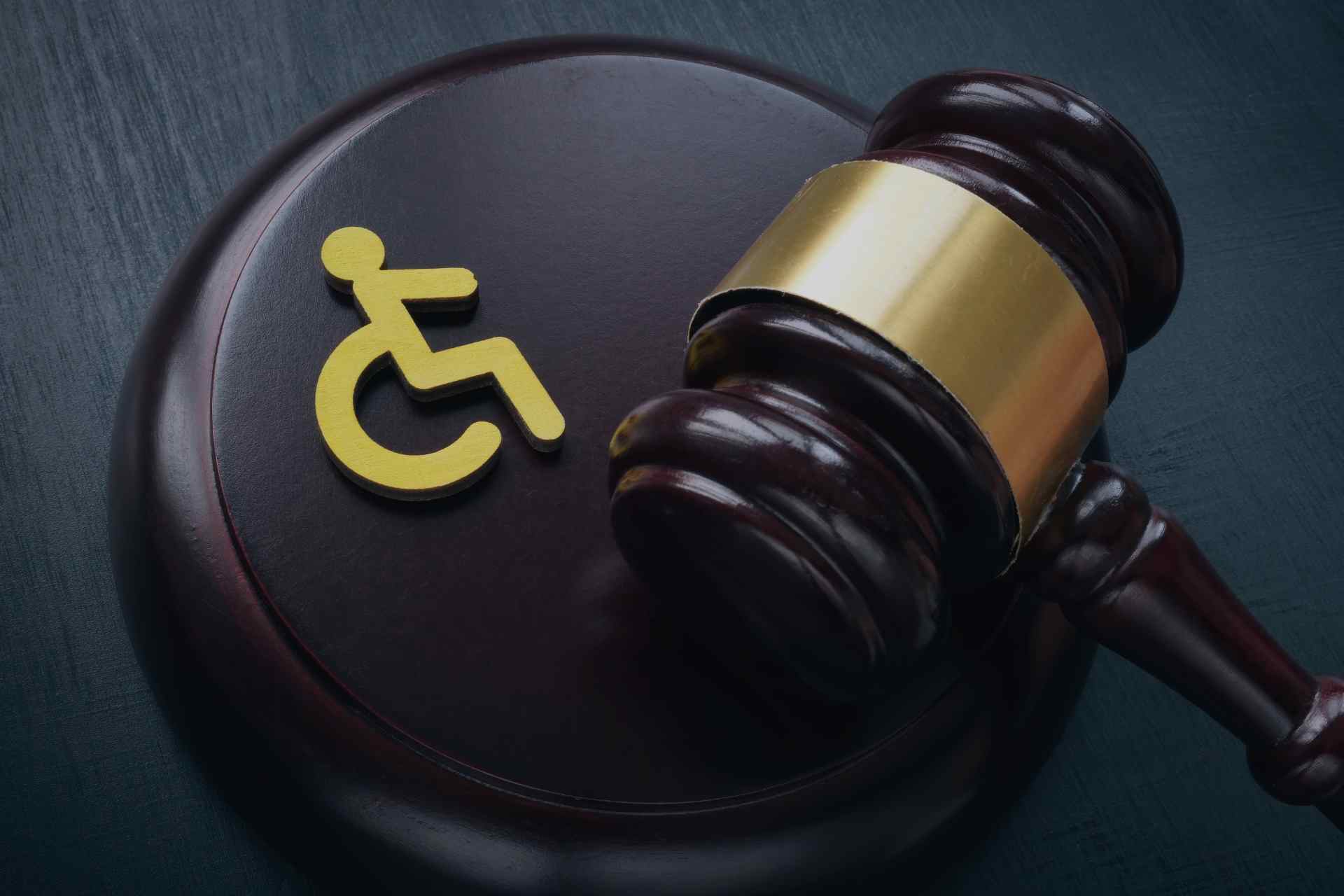A wooden gavel resting on a surface with a yellow disability symbol, representing legal issues related to personal injury 