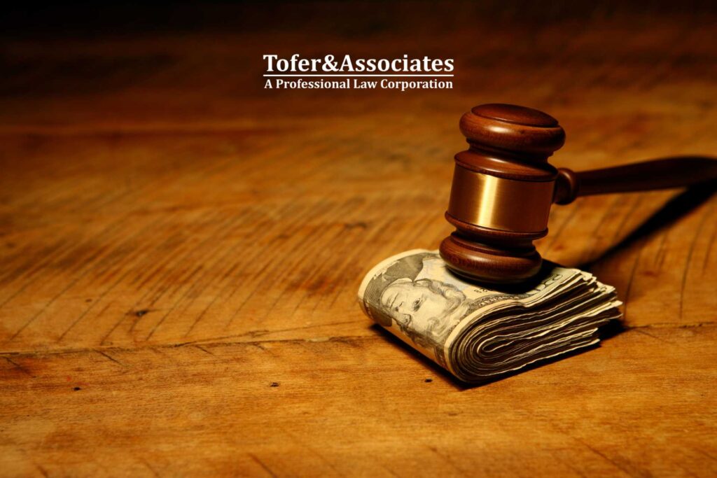 Stack of U.S. dollar bills under a gavel on a wooden surface, , symbolizing financial compensation for personal injury settlements in California.