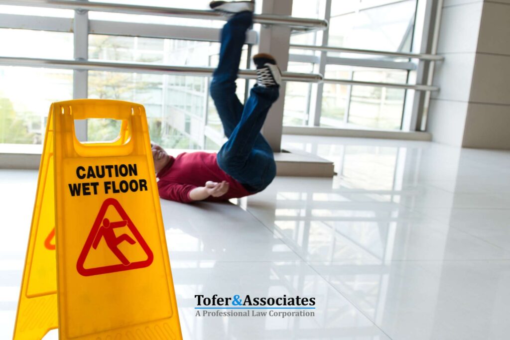 Person slipping on a wet floor beside a caution sign, illustrating a slip and fall injury in a modern building