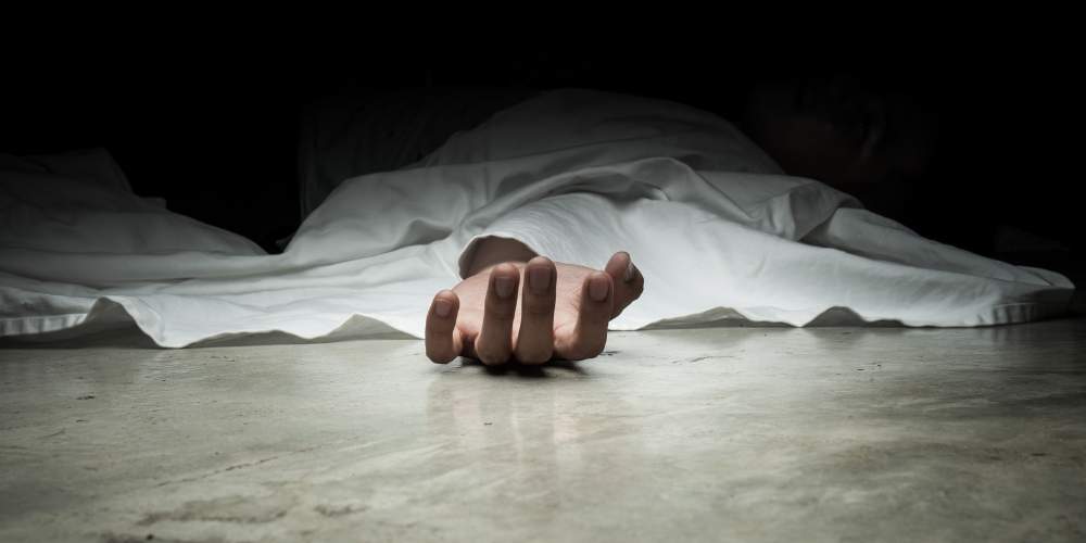 Close-up of a deceased person's hand under a white sheet on the floor, symbolizing a wrongful death incident