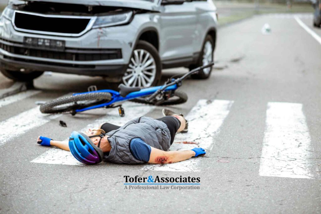 Man lying injured on a crosswalk after a bicycle accident with a car nearby