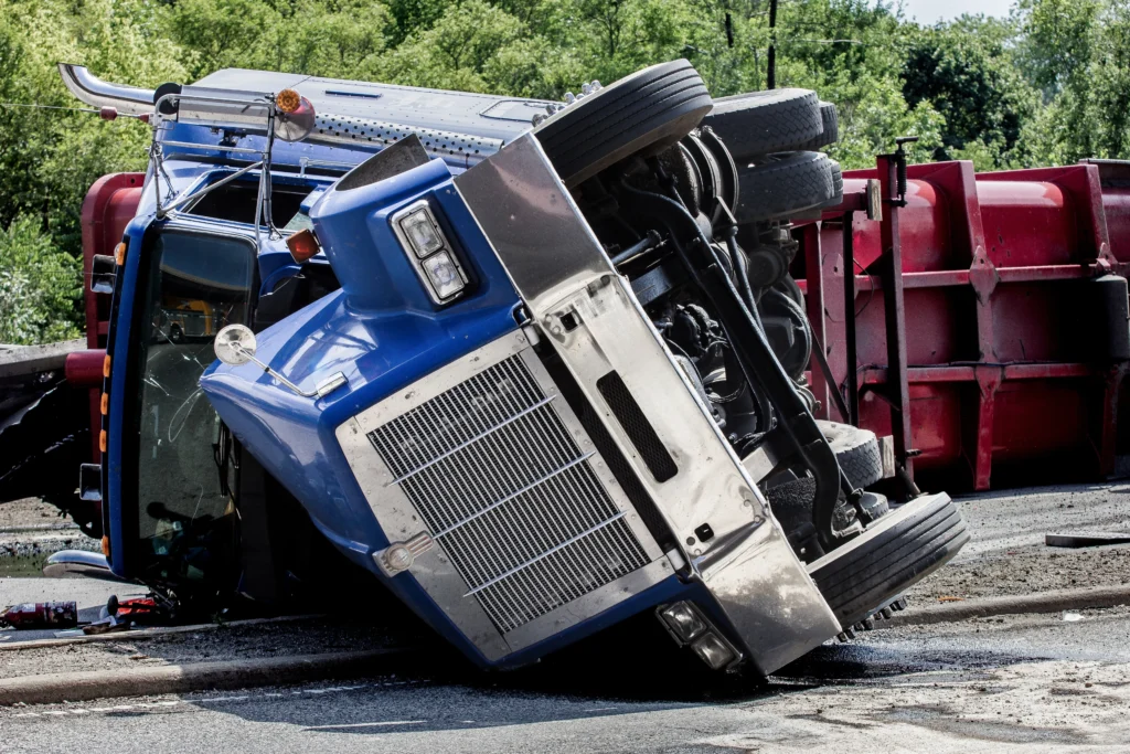 truck overturned on a road, leaning on its side with visible damage